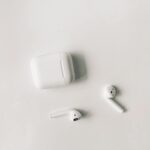 Clean minimalist flat lay featuring wireless earbuds and case on a white background.