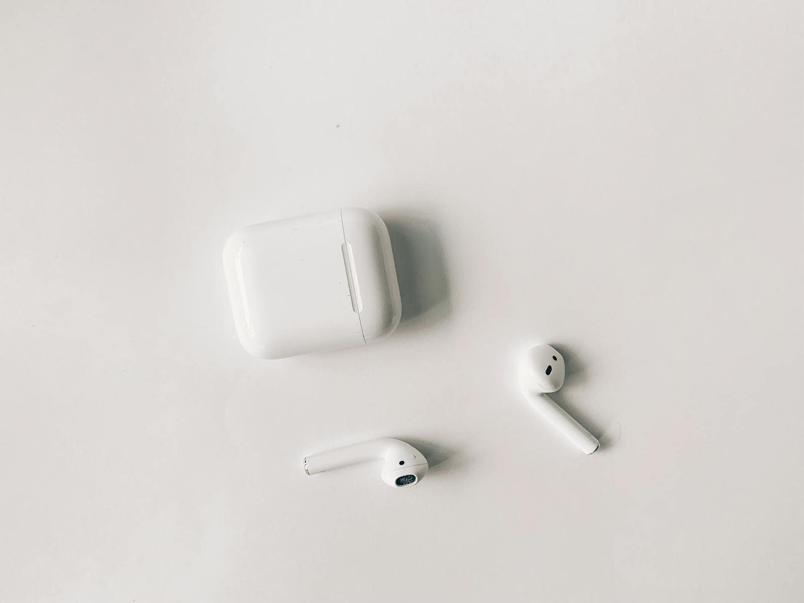 Clean minimalist flat lay featuring wireless earbuds and case on a white background.