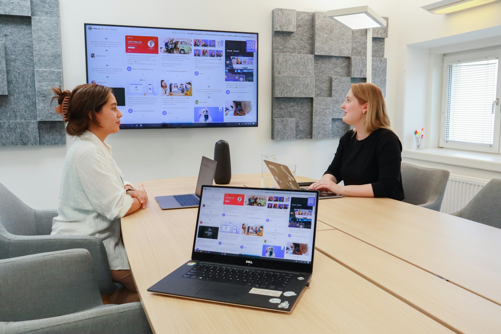 two women sitting at a table with laptops