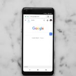 black Android smartphone showing google site on white surface