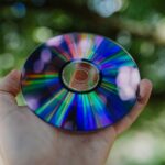 selective focus photography of person holding compact disc