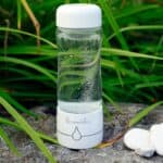 a glass bottle with water inside sitting on a rock