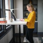 woman in yellow long sleeve shirt and black pants standing beside white table